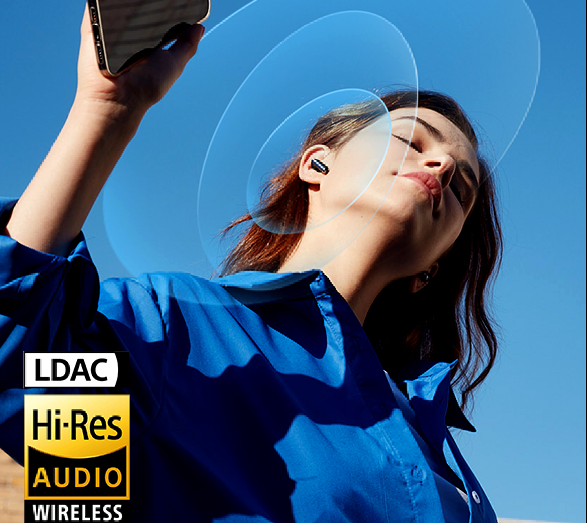 Kobieta z bezprzewodowymi słuchawkami Hi-Res Audio pod niebieskim niebem, ciesząca się muzyką dzięki technologii bezprzewodowej LDAC.