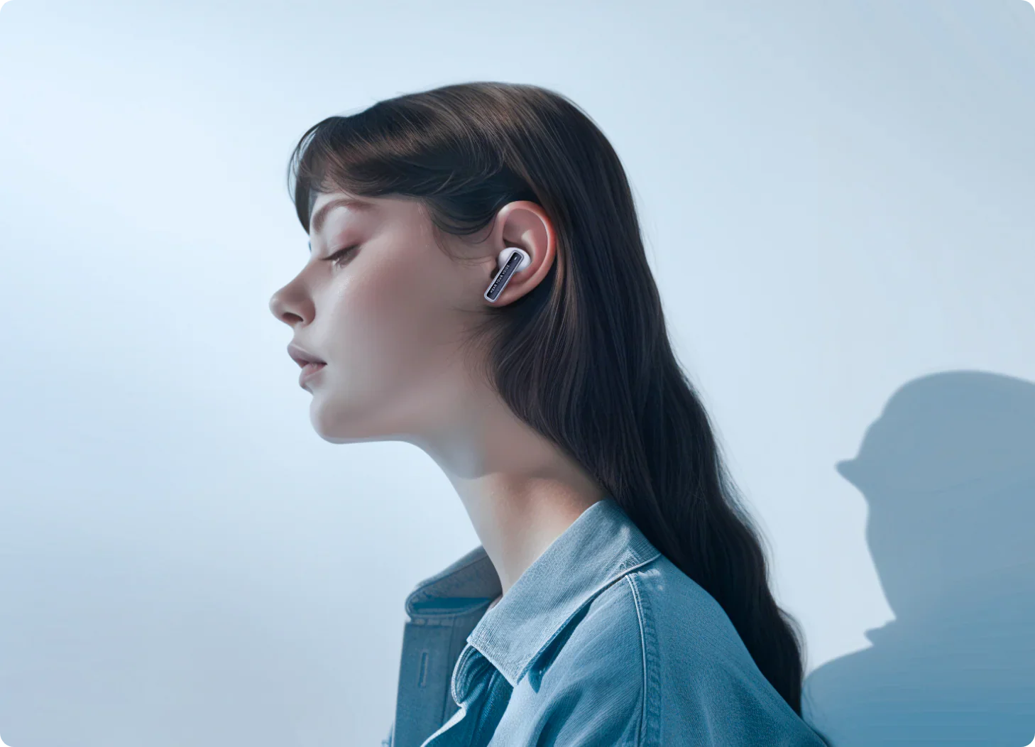 Kobieta w białych słuchawkach Bluetooth w dżinsowej kurtce, widok z boku
