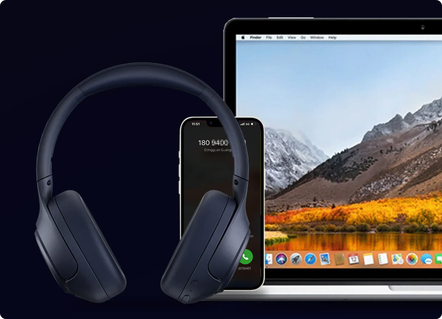 Ciemnoniebieskie słuchawki nauszne obok iPhone’a i MacBooka na tle gór.