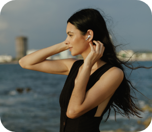 A woman walking on the beach wearing QCY HT10