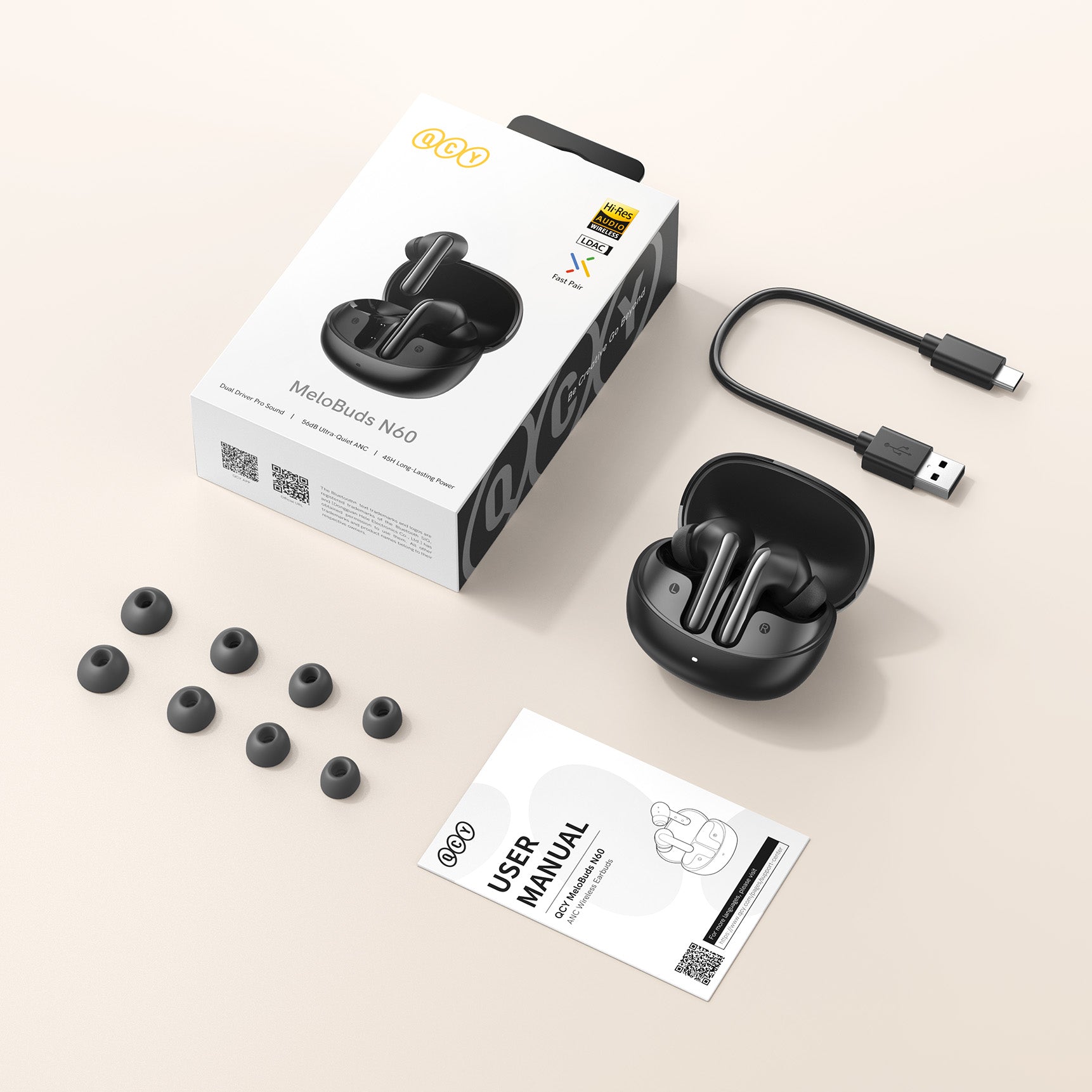 QCY MeloBuds N60 Bezprzewodowe słuchawki douszne z etui ładującym, kablem USB, zapasowymi wkładkami dousznymi i instrukcją obsługi na jasnym tle